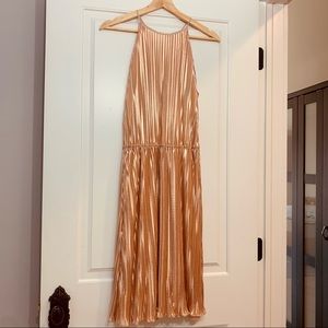 Pleated halter neck dress in a shimmering iridescent light copper color.